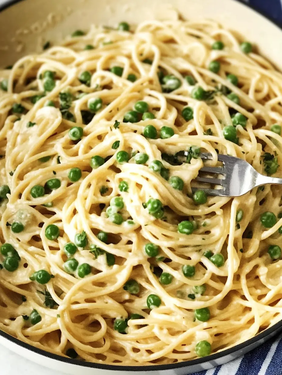 Une fourchette est plantée dans un bol de pâtes avec des petits pois.